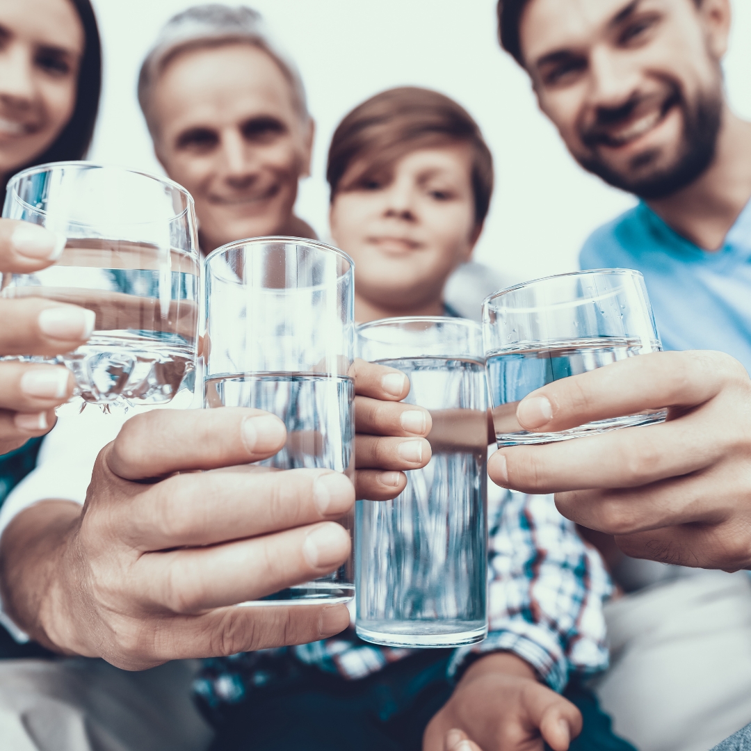 Four people in the background each holding a clear, glass cup full of drinking water